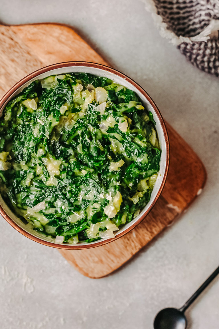 Keto creamed spinach in a bowl on a wooden board